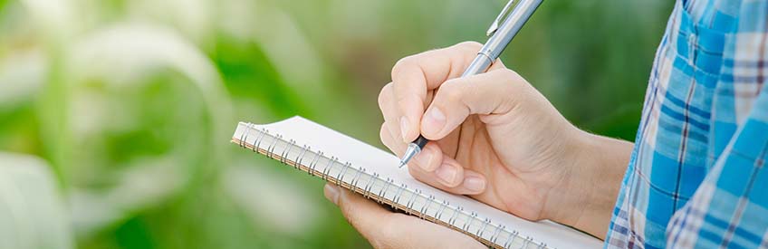 Man on farmland making notes on clipboard