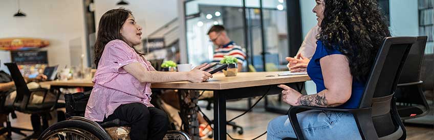 Caregiver working with individual in wheelchair at table