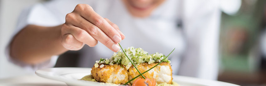 smiling chef adding finishing touches to dish