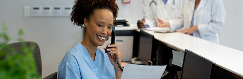 Person on phone behind the desk of a medical office