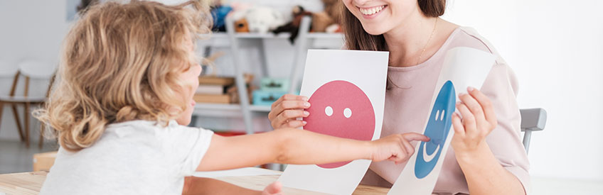 Smiling counselor holding pictures during meeting with young patient