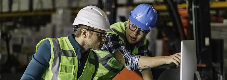 Supervisor directing apprentice in industrial setting